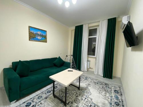 sala de estar con sofá verde y mesa en Rusel Hotel en Aktau