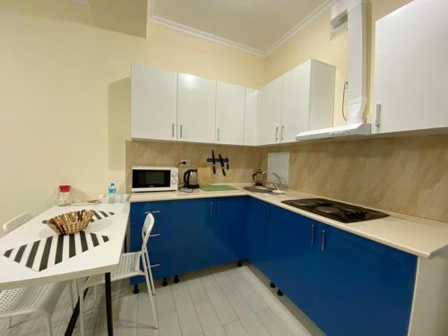 cocina con armarios azules y blancos y microondas en Rusel Hotel en Aktau