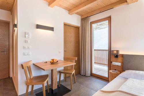 a bedroom with a table and chairs and a bed at Villa Solinda App Rossini in Selva di Val Gardena