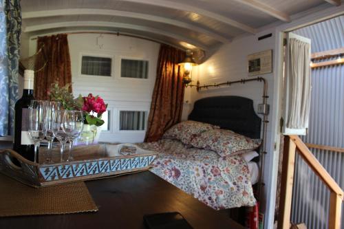 1 dormitorio con 1 cama y 1 mesa con copas de vino en The Edwardian Caravan 'Dora', en Lampeter