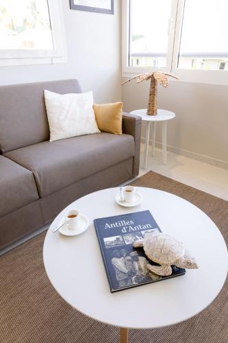 a living room with a white coffee table with a book at Eden Roc Villas in Le Diamant