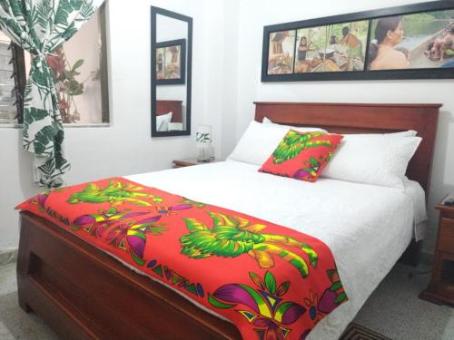een slaapkamer met een bed met een rode en groene deken bij Etnias Hotel tematico in Quibdó