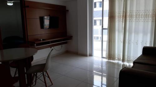 a living room with a table and a tv and a couch at Jockey Family Chamonix 2 in Vila Velha