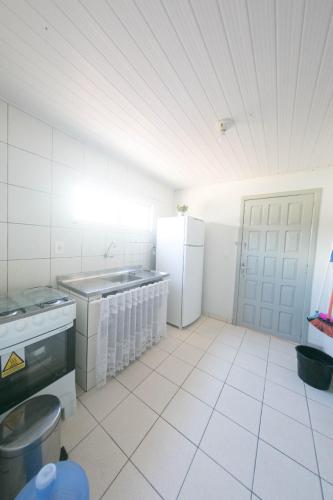 a kitchen with white tile floors and white appliances at Res Diego Marcelo DK4 - Casa Completa, Piscina, Churrasqueira e Sinuca in Itapema