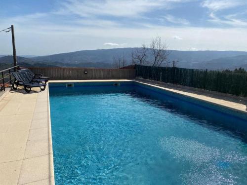 uma piscina azul com um banco e montanhas ao fundo em casa da alegria em Urgueira