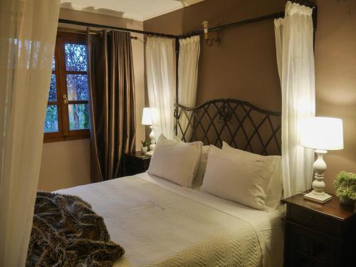 a bedroom with a bed with white pillows and a window at Dryades Suites in Synikia Mesi Trikalon