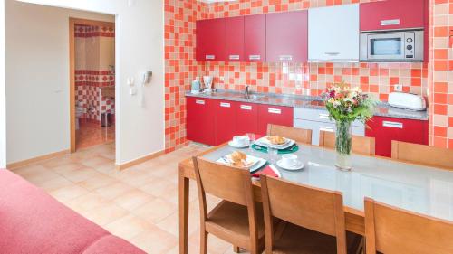 a kitchen with red cabinets and a table and chairs at Alfagar Alto da Colina in Albufeira
