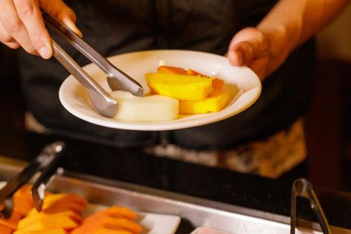 a person holding a plate of food with fruit at Interclass Florianópolis in Florianópolis