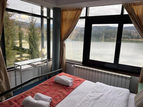 1 dormitorio con ventana grande y 1 cama con 2 toallas en Vila Franceză - Cazare cu jacuzzi pe malul lacului Colibița en Colibiţa