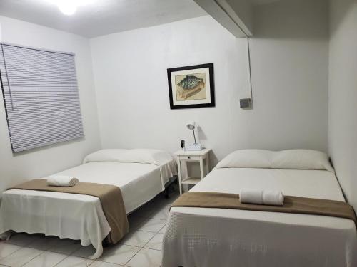 1 Schlafzimmer mit 2 Betten, einem Tisch und einem Fenster in der Unterkunft CRAB ISLAND ADVENTURES APARTMENTS in Vieques