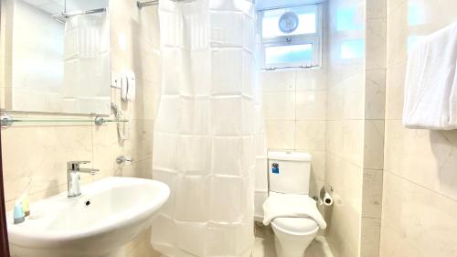 a white bathroom with a sink and a toilet at Concorde Inn Hotel in Dubai