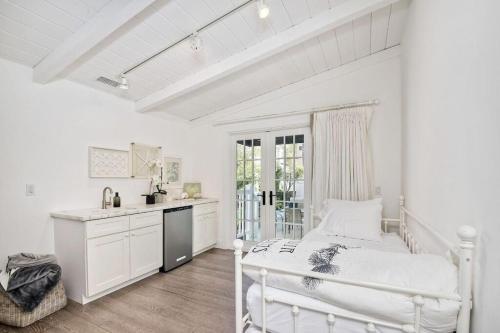 a white bedroom with a bed and a kitchen at Ocean Views, Across The Street From Beach, Private Patio in Carlsbad