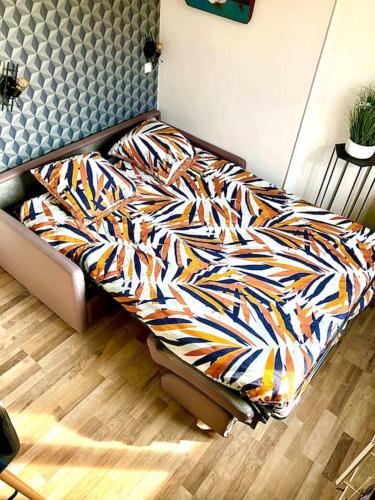 un lit avec une couette colorée dans une chambre dans l'établissement Le Road 66, proche centre ville, parking gratuit., à Sens