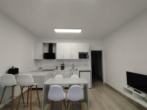a white kitchen with a table and white chairs at HORIZON in Arzúa