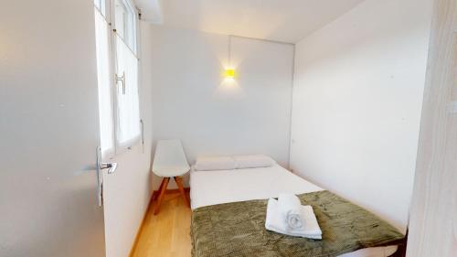 サン・ジル・クロワ・ド・ヴィにあるAppartement Les Embrunsのベッドと窓が備わる小さな白い客室です。