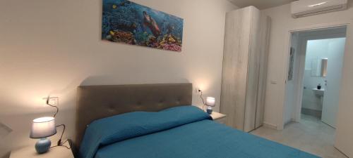Un dormitorio con una cama azul y una pintura en la pared en Appartamento Mare&Castello, en Castelsardo