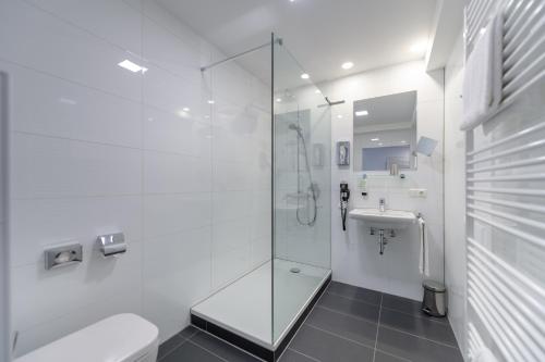 a bathroom with a shower and a toilet and a sink at CiTTy Hotel Schweinfurt in Schweinfurt