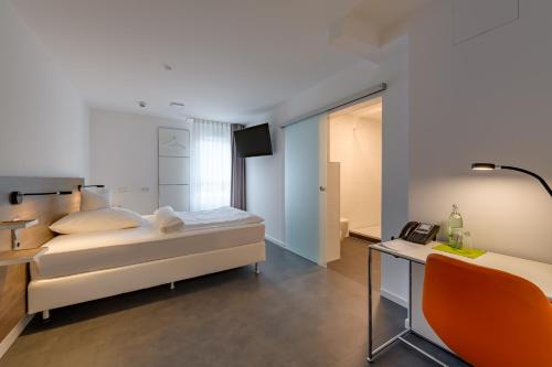 a bedroom with a bed and a desk with a phone at CiTTy Hotel Schweinfurt in Schweinfurt