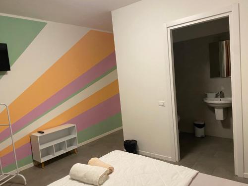 ein Schlafzimmer mit einer Regenbogenwand mit einem Bett und einem Waschbecken in der Unterkunft Michelangelo home in Trient