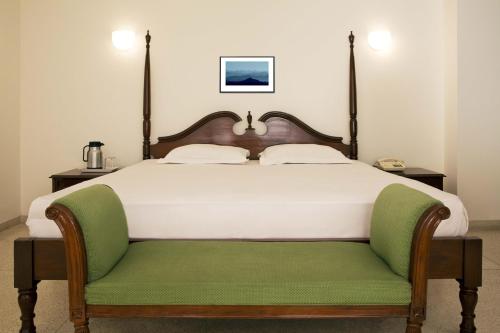 a bedroom with a large bed with a green bench at Hotel Alpana in Haridwār