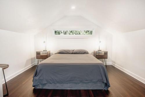 a white bedroom with a bed and two night stands at Olde Village Loft - Unique Park Circle Experience in Charleston