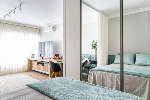 1 dormitorio con 2 camas, escritorio y espejo en K-Platz 406 - Studio Elegante e Moderno na Melhor Localização do Continente en São José