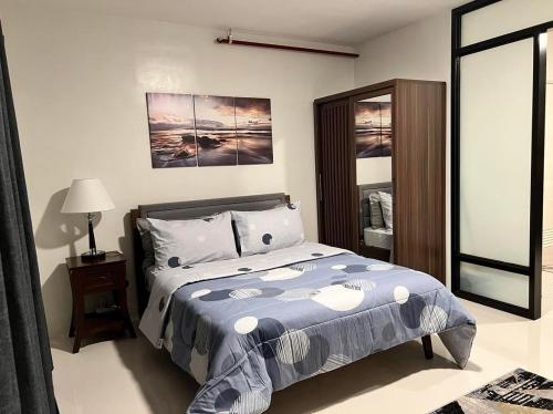 a bedroom with a bed with a blue comforter and a mirror at 7F Majorca, Camella Manors Bacolod Condo in Bacolod