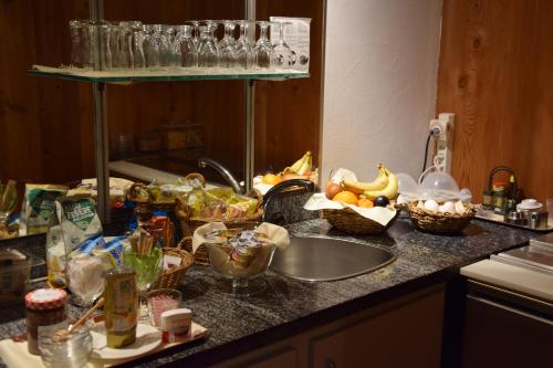 a kitchen counter with a sink and a bunch of food at Hotel Santana in Roveredo