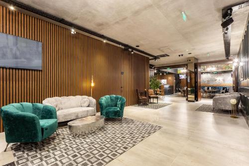 a lobby with a couch and chairs and a tv at Abrazo Sofia Hotel by HMG in Sofia