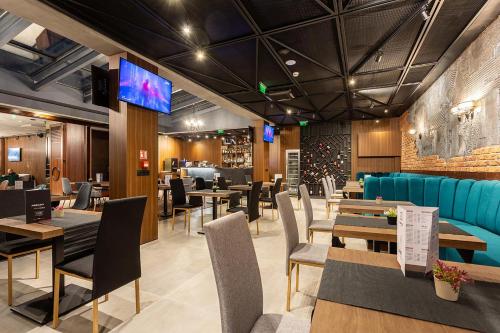 a restaurant with tables and chairs and a tv at Abrazo Sofia Hotel by HMG in Sofia