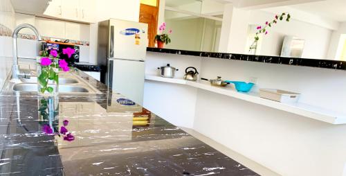 a kitchen with white appliances and purple flowers in a vase at STYLISH & Spacious Apartment in Cusco