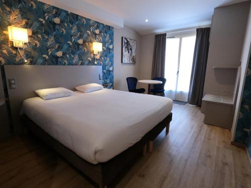 1 dormitorio con 1 cama blanca grande y pared azul en Beaune Hôtel en Beaune