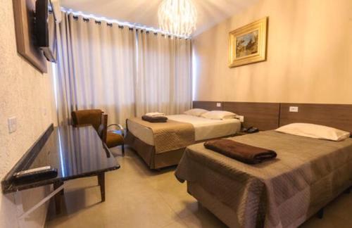 a hotel room with two beds and a television at HOTEL PIACENTINI in Campo Mourão