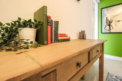 einem Holztisch mit Büchern und einer Topfpflanze darauf in der Unterkunft Luxurious 2 Bedroom Apartment in City Centre in Nottingham