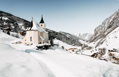 a church covered in snow in a mountain at ONKL XONNA Premium Alpin Chalets in Hüttschlag