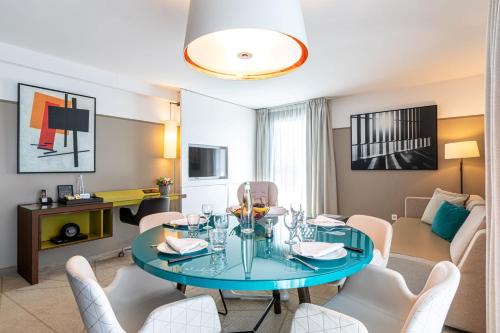 Fraser Suites Paris La Défense في كوربفوا: غرفة معيشة مع طاولة وكراسي زرقاء