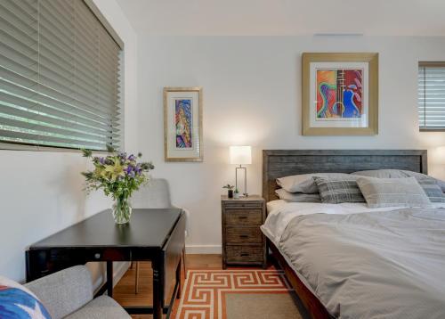 Un dormitorio con una cama y una mesa con un jarrón de flores en The Marymaker by Lodgewell - It's Super Suite Y'all en Austin