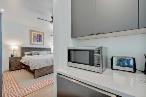 a kitchen with a microwave and a bedroom with a bed at The Marymaker by Lodgewell - It's Super Suite Y'all in Austin