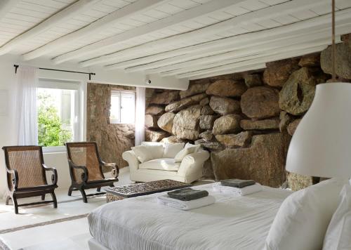 - une chambre dotée d'un mur en pierre avec un lit et des chaises dans l'établissement Paradise Estate Community, à Paraga