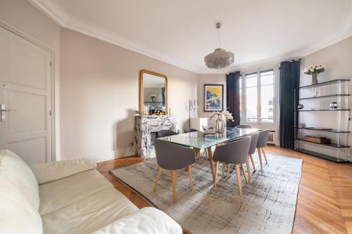 une salle à manger avec une table et des chaises en verre dans l'établissement Spacieux et élégant appartement Porte des ternes, à Paris