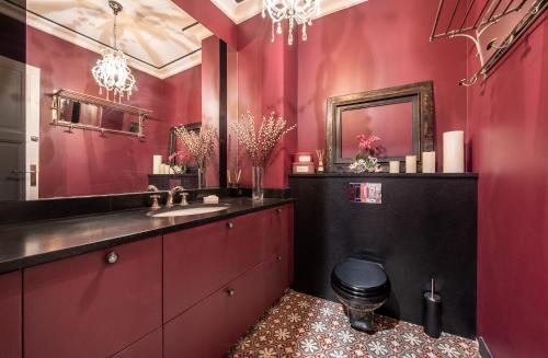 bagno con pareti rosse, servizi igienici e lavandino di Spacieux et élégant appartement Porte des ternes a Parigi