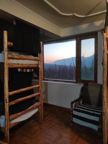 ein Schlafzimmer mit einem Etagenbett, einem Stuhl und einem Fenster in der Unterkunft The Hideout - Hiraeth in Manali