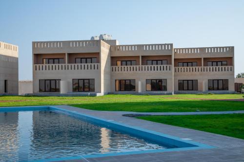 a building with a swimming pool in front of it at Continent Hotel Al Uqayr فندق كونتننت العقير 