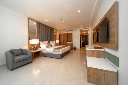 ein Schlafzimmer mit einem Bett, einem Stuhl und einem TV in der Unterkunft Continent Hotel Al Uqayr فندق كونتننت العقير 