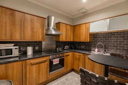a kitchen with wooden cabinets and a counter top at Two Bedroom Apartment Within Walking Distance to City Centre in Edinburgh