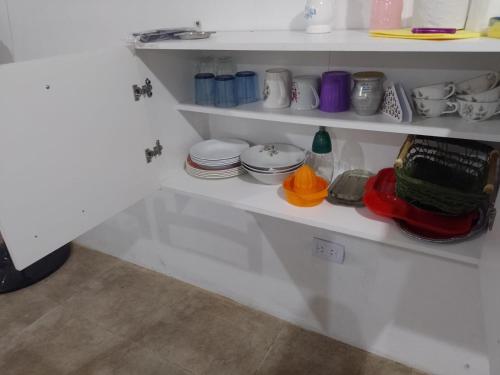 a white shelf with dishes and cups on it at Brisas del Mar ll in San Clemente del Tuyú