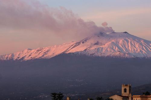 a snow covered mountain in the distance with a clock tower at Hotel Villa Paradiso in Taormina