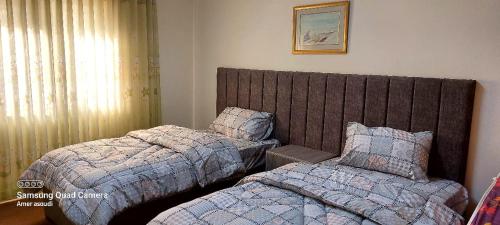 a bedroom with two beds and a large headboard at noor apartment in Wadi Musa