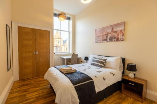 1 dormitorio con cama y ventana en New 2 bed apartment with stunning views of Arthur Seat Mountain en Edimburgo