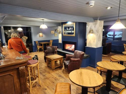 a bar with tables and chairs and a fireplace at The Swan - A Colombo Edition Hotel in Ely